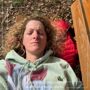 Frau ruht auf einer Bank in der Sonne - Moment der Regeneration als Symbol für Selbstfürsorge, Energie und Stressregulation im Kontext von Burnout Prävention.